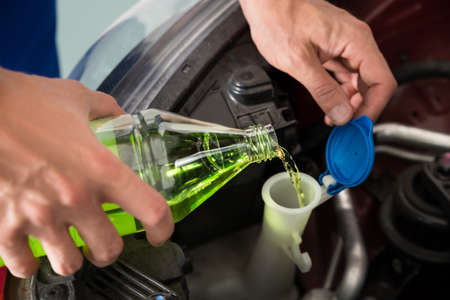 Close-up Of Mechanic Pouring Windshield Washer Fluid