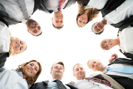 Directly below portrait of confident business team standing in huddle against white backgroundの写真素材