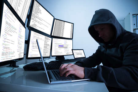 Hacking laptop against multiple monitors at desk