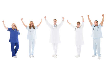 Full length portrait of happy medical team standing with arms raised against white backgroundの写真素材