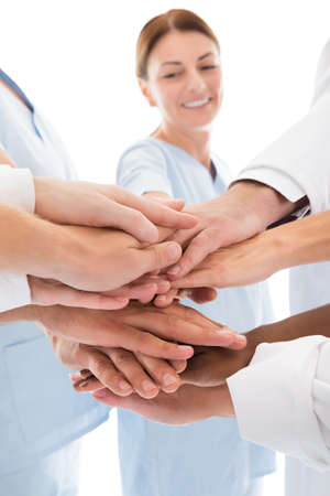 Cropped image of medical team stacking hands against white background