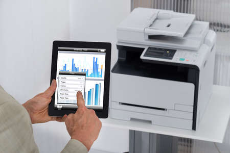 Cropped image of businessman giving print command on digital tablet in office