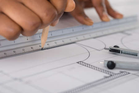 Close-up Of A Person's Hand Drawing Blue Print With Pencil
