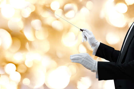 Cropped image of music conductor's hand holding baton against colored backgroundの写真素材