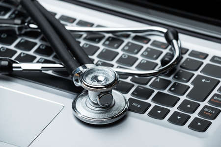 Closeup photo of stethoscope on laptop keyboardの写真素材