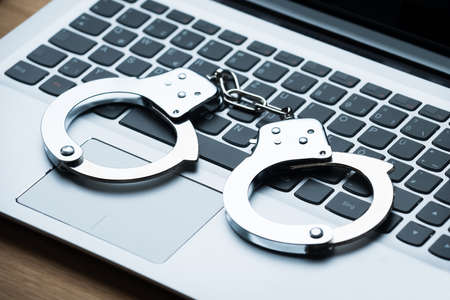 Closeup of handcuffs on laptop at table