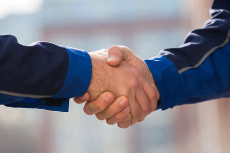 Cropped image of male architects shaking hands outdoors