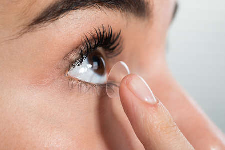 Closeup of young woman wearing contact lens at homeの写真素材