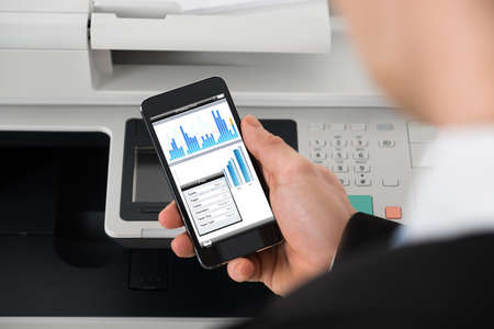 Cropped image of businessman giving print command on smart phone in office