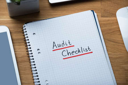 High angle view of audit checklist written on notepad at office deskの写真素材