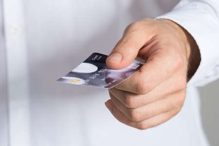Midsection of businessman holding credit card in office