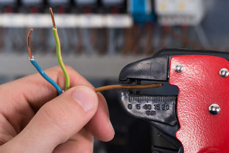 Close-up Of Electrician Hands Stripping Electrical Wiresの写真素材