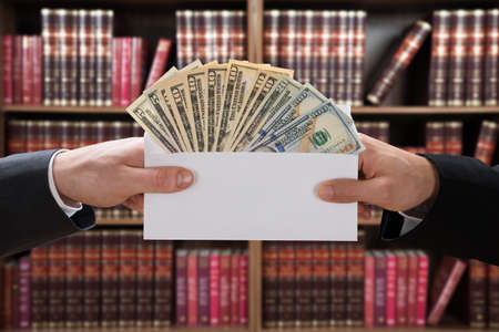 Cropped image of man's hands passing bribe to judge in envelope at courtroom
