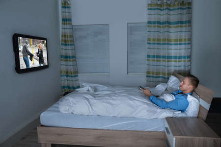 Photo Of Man Lying On Bed Watching Televisionの写真素材