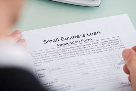 Close-up Of Person Hand Over Small Business Loan Application Form