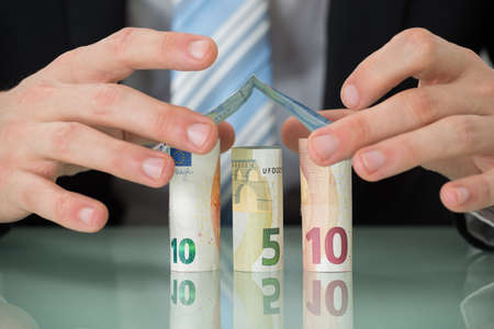 Close-up Of Businessman Hand Making House Of Euro Banknotesの写真素材