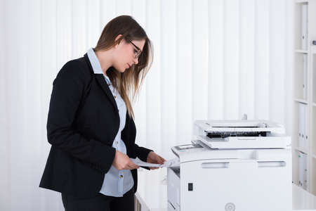 Young Businesswoman Using Copy Machine At The Officeの写真素材