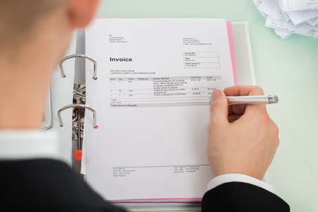 Young Businessman Calculating Tax At Office Deskの写真素材