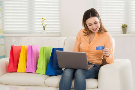 Happy Woman Using Card While Shopping At Laptopの写真素材