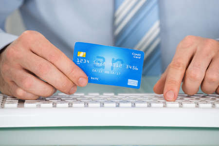 Close-up Of A Businessperson With Credit Card Using Keyboard
