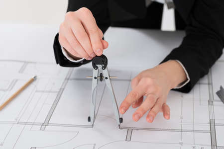 Close-up Of Female Architect Hands Holding Compass On Blueprint