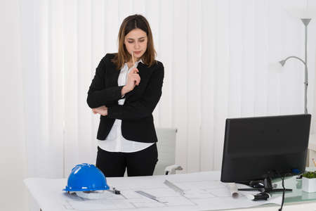 Young Female Architect Working On Blue Print In Office