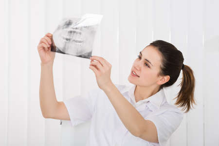 Young Female Dentist Looking At Dental X-ray In Clinic