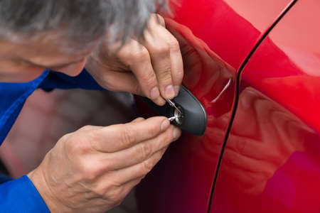 Close-up Of Person Hand Holding Lockpicker To Open Car Door