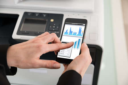 Close-up Of Businesswoman Giving Print Command On Smart Phoneの写真素材