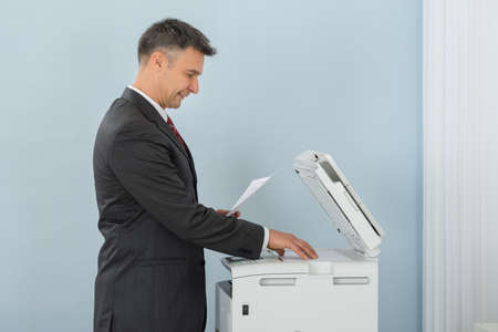Businessman Keeping Paper On Photocopy Machine In Officeの写真素材