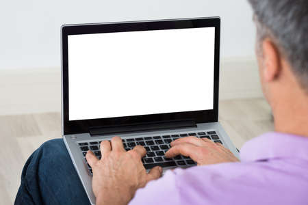Close-up Of Mature Man Using Blank Screen Laptop At Homeの写真素材