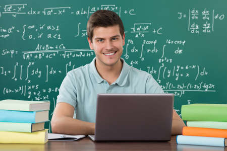 Young Man Using Laptop While Studying In Classroom