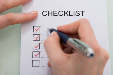 Close-up Of Woman Marking On Checklist Form With Red Penの写真素材