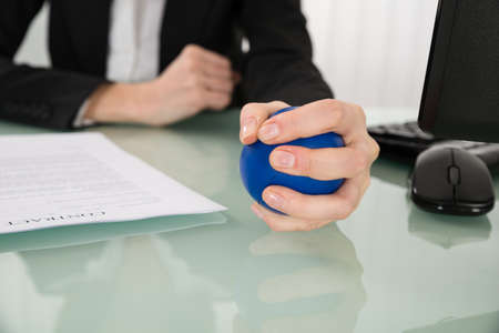 Close-up Of Businesswoman Pressing Stressball In Officeの写真素材