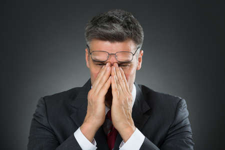 Portrait Of Stressed Businessman With Hands Covering The Faceの写真素材