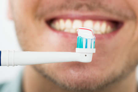 Close-up Of Young Man Teeth With Electric Toothbrushの写真素材