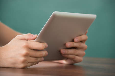 Close-up Of Person Hand Holding Digital Tablet At Deskの写真素材