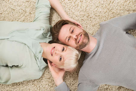 Close-up Of Happy Couple Lying On The Carpet At Homeの写真素材