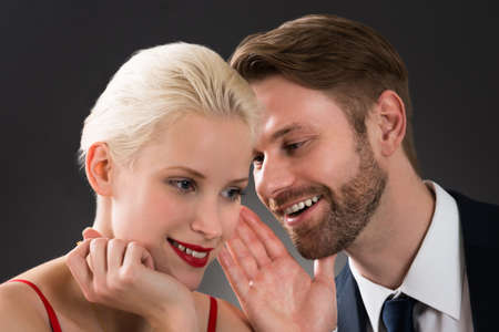 Portrait Of Young Man Whispering In Woman's Ear At A Restaurantの写真素材
