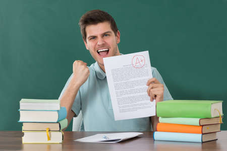 Successful Happy Young Man Showing Examination Paperの写真素材