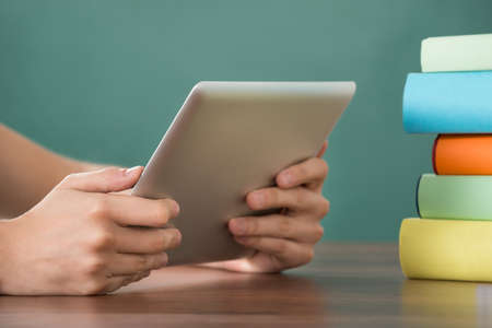 Close-up Of Person Hand Holding Digital Tablet At Deskの写真素材
