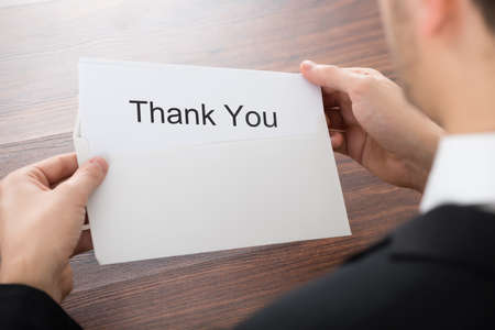 Close-up Of Businessman Holding Thank You Card In Envelopeの写真素材