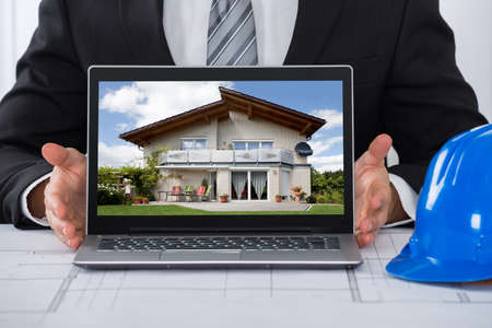 Close-up Of An Architect Showing His Laptop Over Blue Print In Officeの写真素材