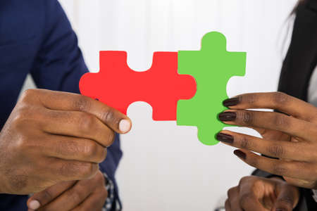 Close-up Of Man And Woman Holding Puzzle Piecesの写真素材