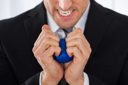 Close-up Of Businessman Pressing Stress Ball In Officeの写真素材