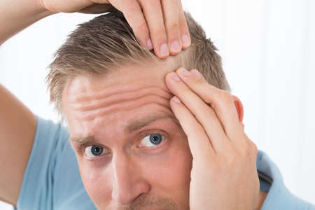 Close-up Of Young Man Examining His Hair At Home