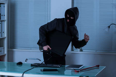 Thief Stealing Computer With Laptop And Digital Tablet On Office Desk