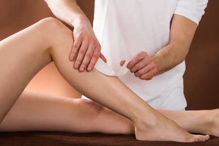 Close-up Of A Woman Getting Her Leg Waxed By Applying Wax Strips At Beauty Spaの写真素材