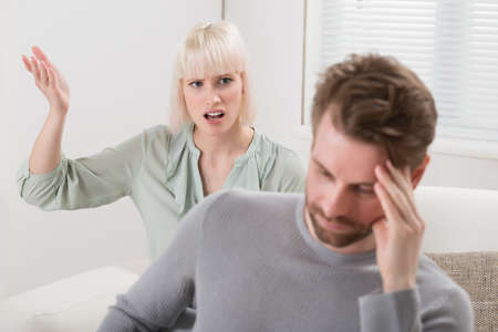 Unhappy Woman Sitting On Sofa Shouting To The Frustrated Man
