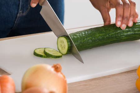 Close-up Of Woman's Hand Chopping Vegetables With Knife In Kitchenの写真素材